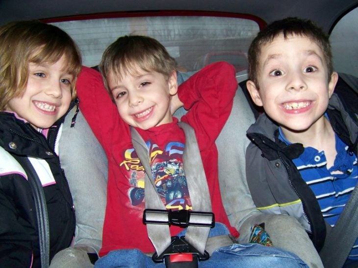 tres niños en un carro