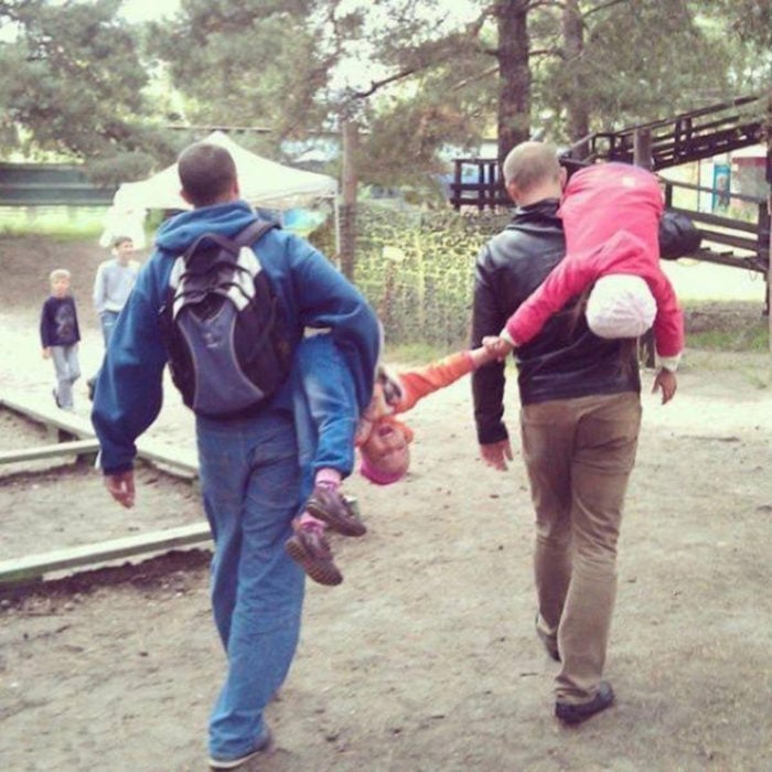 papás cargando a niños que se están dando la mano