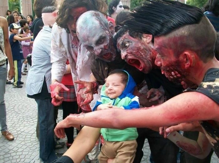 bebé en medio de personas vestidas de zombies