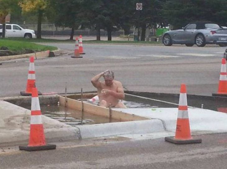 hombre bañándose en un charco de agua en la calle