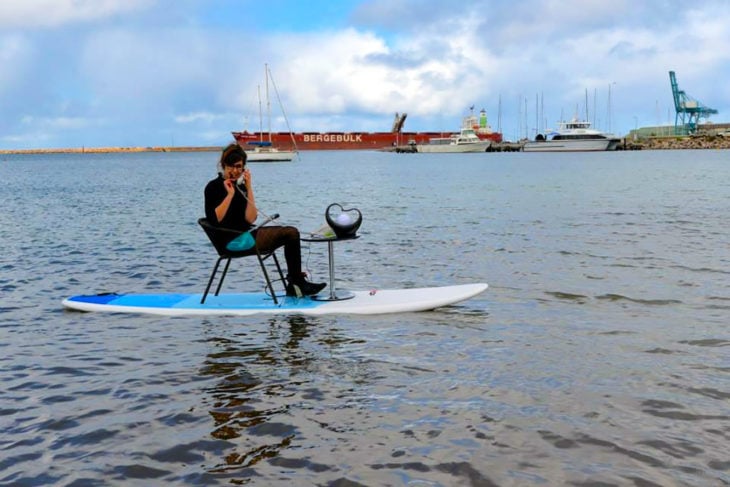 mujer contestando el teléfono en una tabla de surf