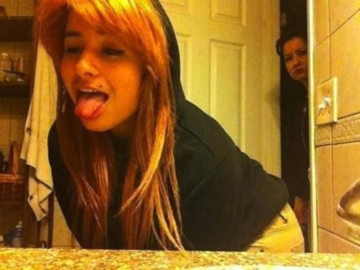 muchacha sacando la lengua se toma selfie mientras su madre la ve extraño