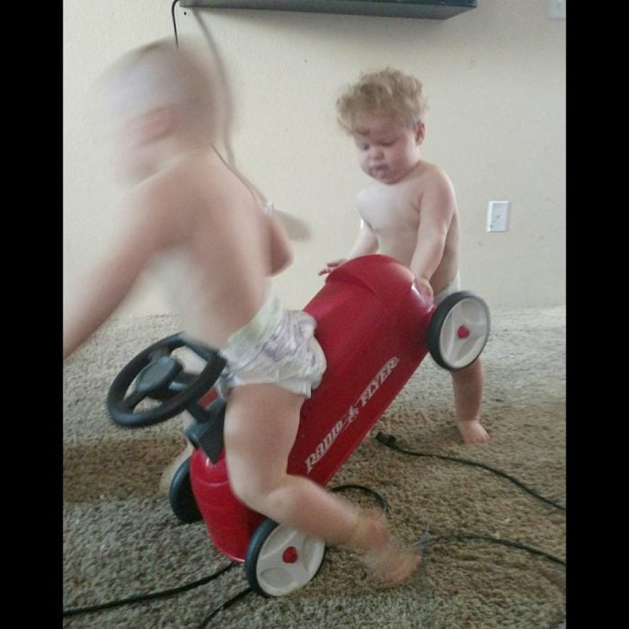 niño tira del carrito a su hermanito 