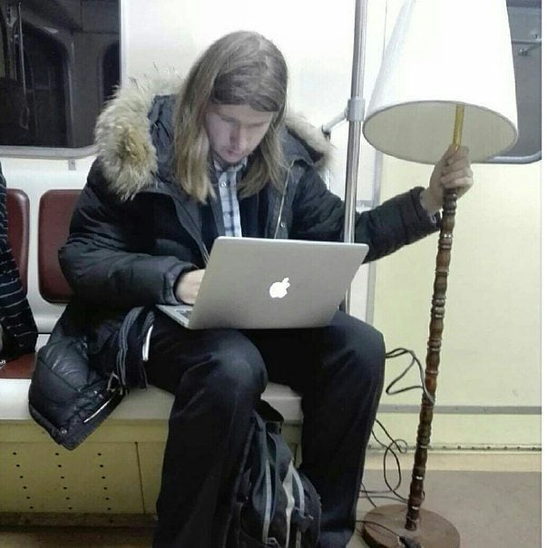hombre con una mac y una lámpara en el metro 