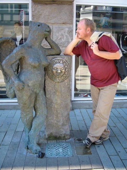 Hombre platicando con estatua de animal mujer