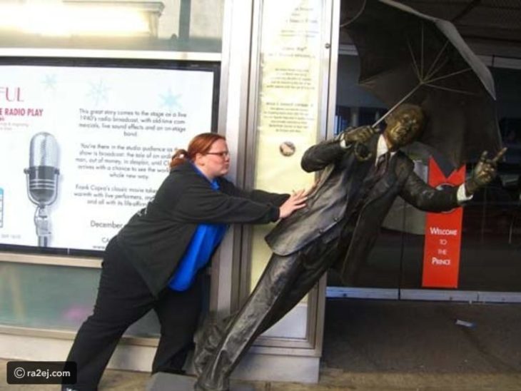 Mujer empujando estatua inclinada