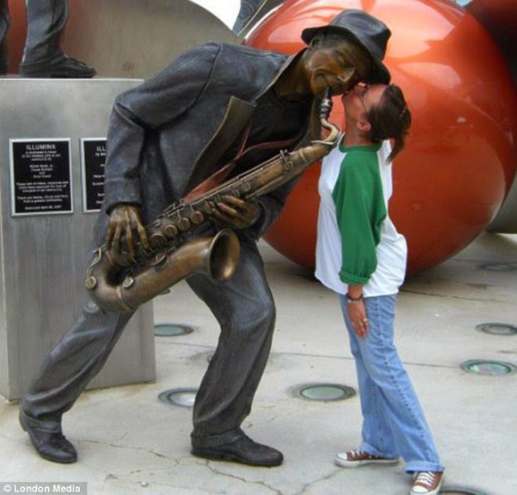 Mujer besando a estatua de musico 