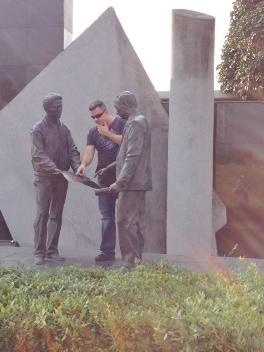 Hombre pidiendo instrucciones a dos estatuas