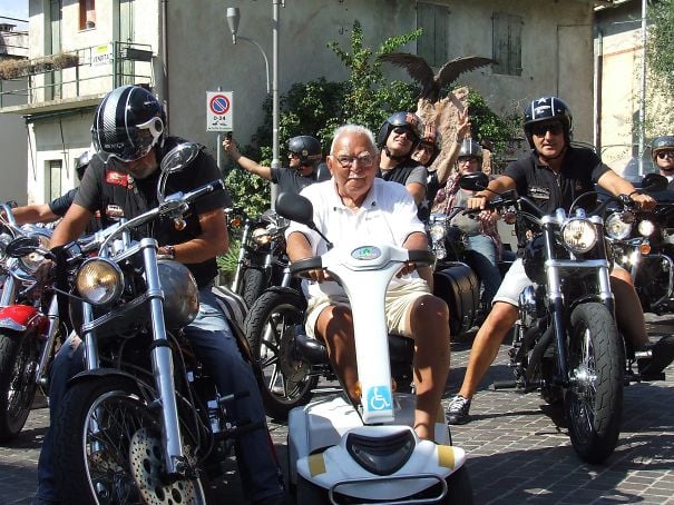 abuelo en silla eléctrica al lado de motociclistas