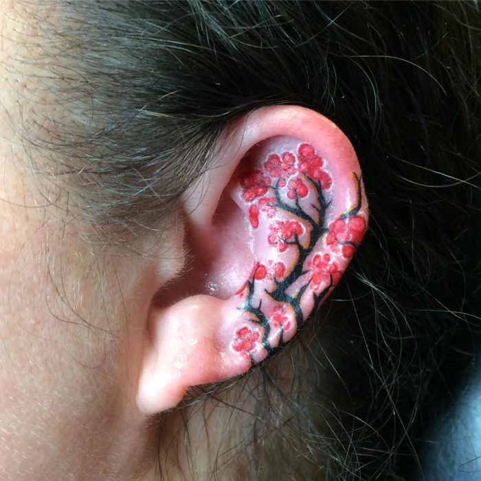 Tatuaje de árbol con flores rojas en el oído 