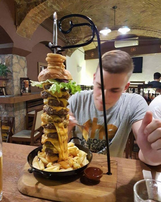 hombre comiendo una hamburguesa de varios pisos