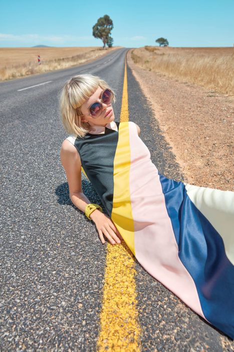 chica con vestido a rayas recostada en carretera