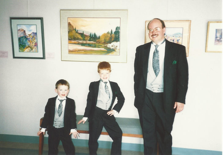 papá y dos hijos con traje, uno posa afeminado