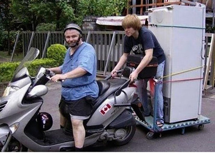 joven sosteniéndose de motocicleta para llevar un refrigerador