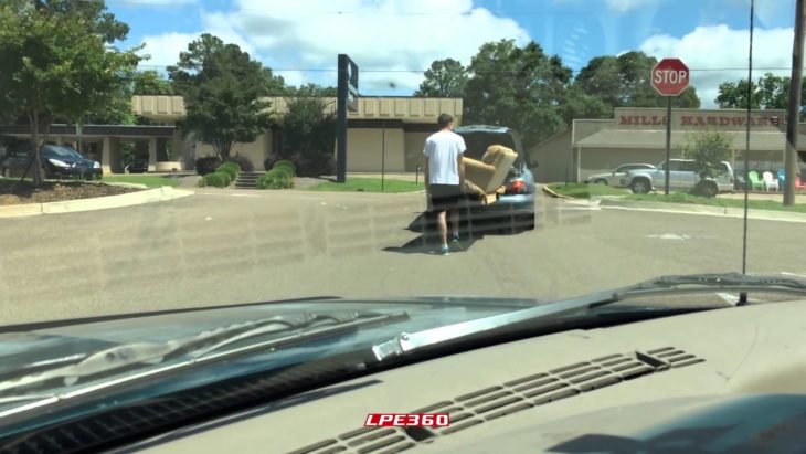 joven intentando meter sillón en la caja de su vehículo