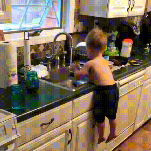 Niño lavando los platos recargado en su panza