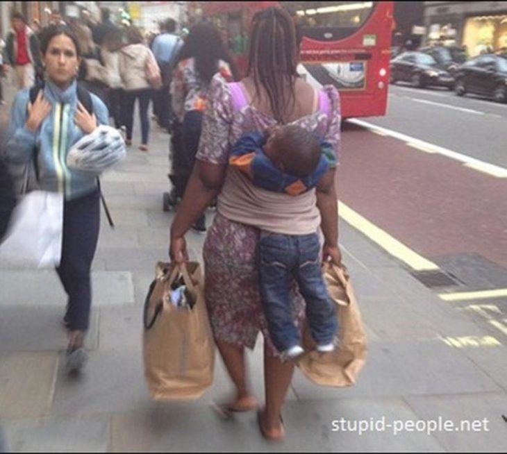 Mujer caminando con bolsas y su hijo se está resbalando