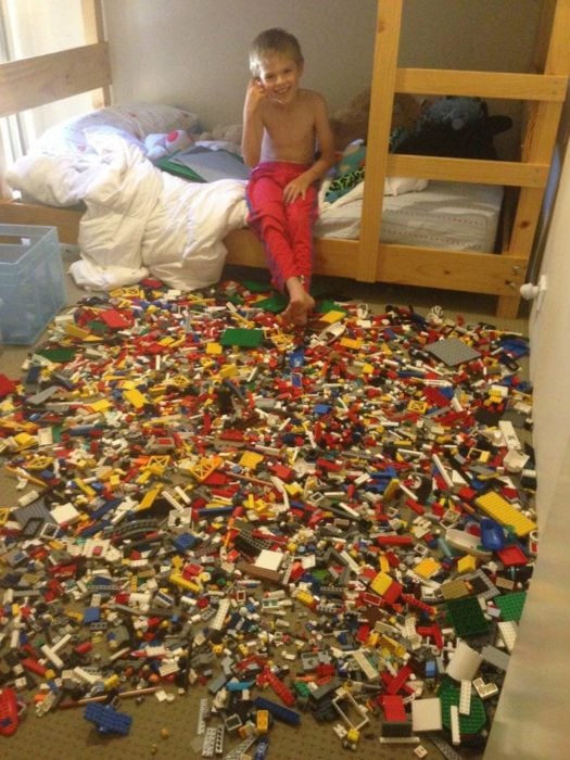 niño con una gran cantidad de legos regados por el suelo