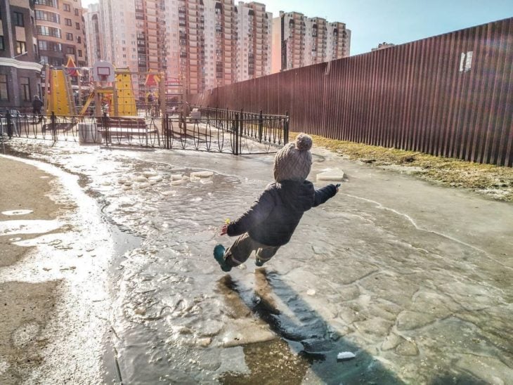 niño a punto de caer por suelo resbaloso por hielo