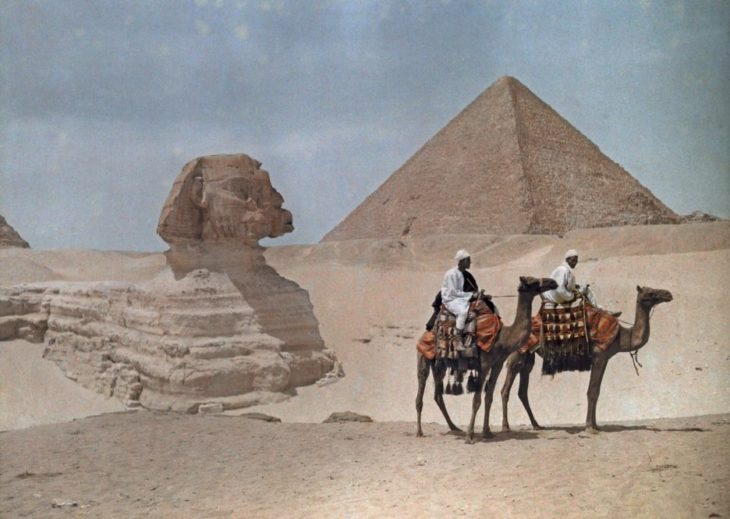 dos hombres montados en camellos cerca de las ruinas de Giza