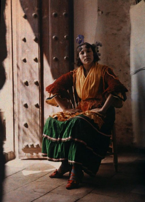 gitana posando en una silla usando su vestido tipico