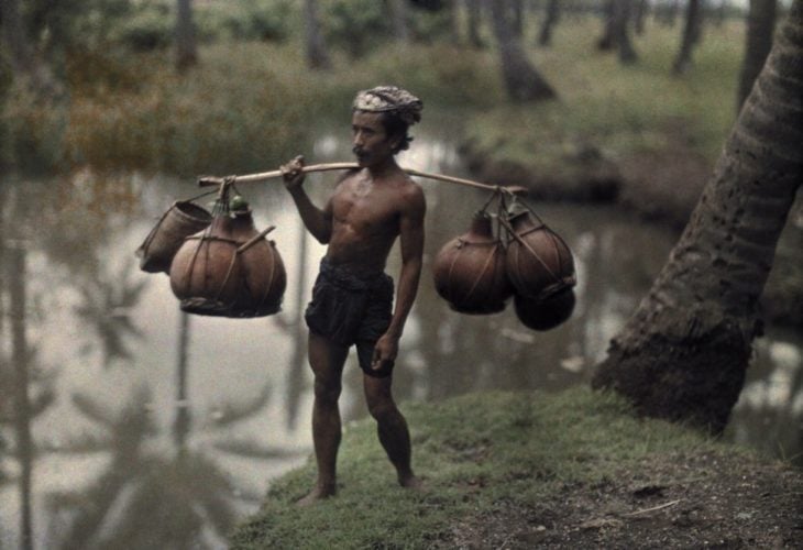 fotografía antigua de mozo cargando agua en calabazas