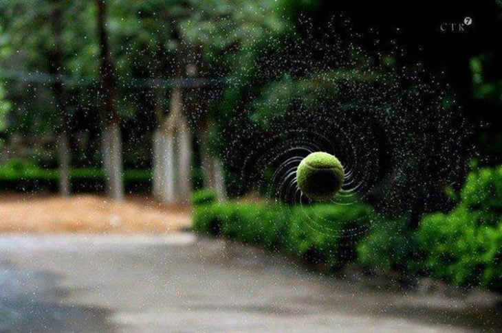 Pelota de tenis girando sacando el agua acumulada