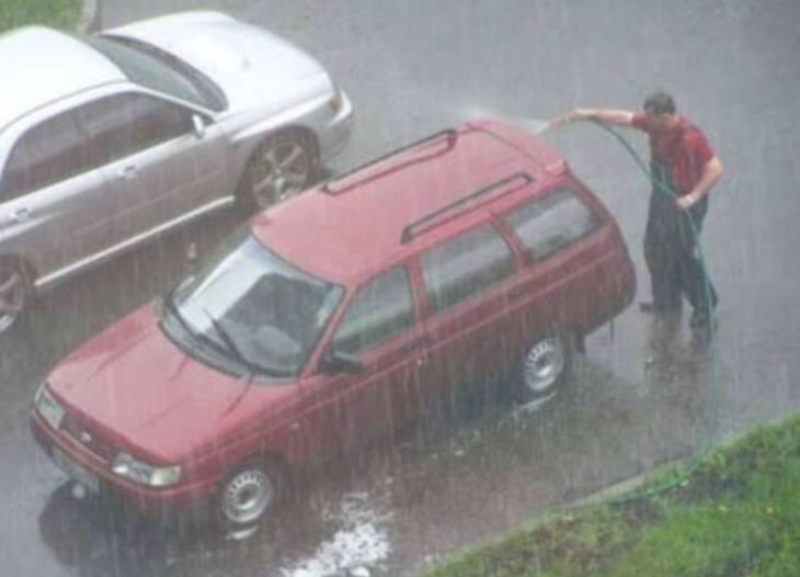 hombre lavando su carro durante la lluvía