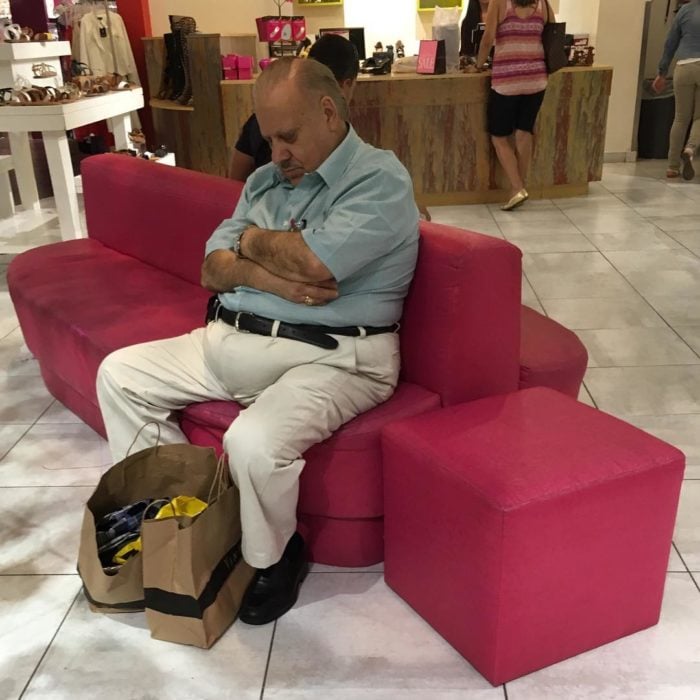 Hombre dormido en sillón rosa de tienda