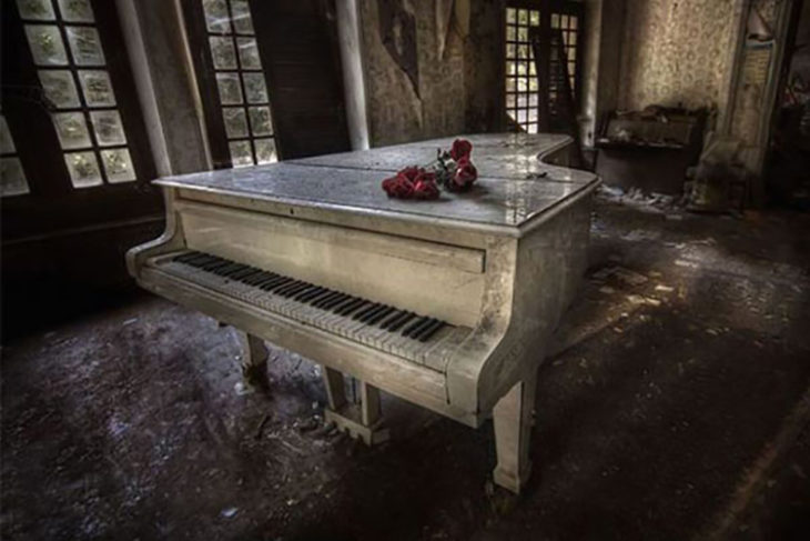 Piano abandonado con flores encima de el