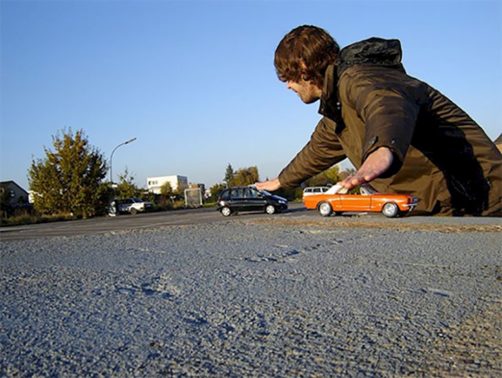 por perspectiva parece que este hombre es gigante pero solo juega con carritos