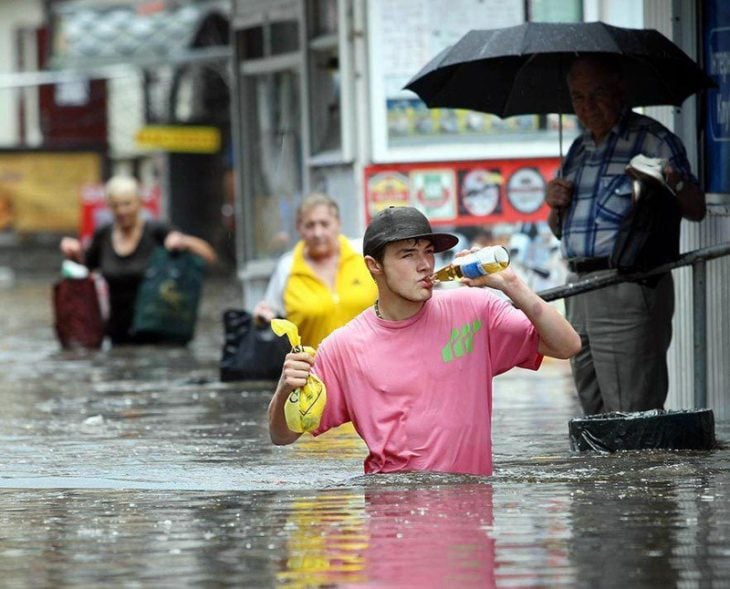 hombre bebiendo cerveza en medio de inundación