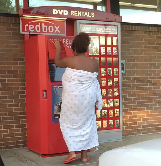 mujer cubierta por cobijas rentando una película