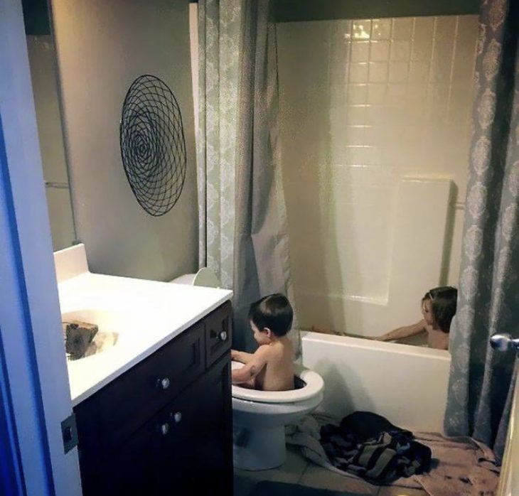 Niño tomando el baño en el escusado 