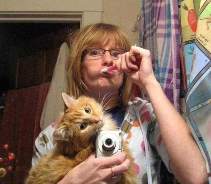 señora cepillando sus dientes, cuidando al gato selfie