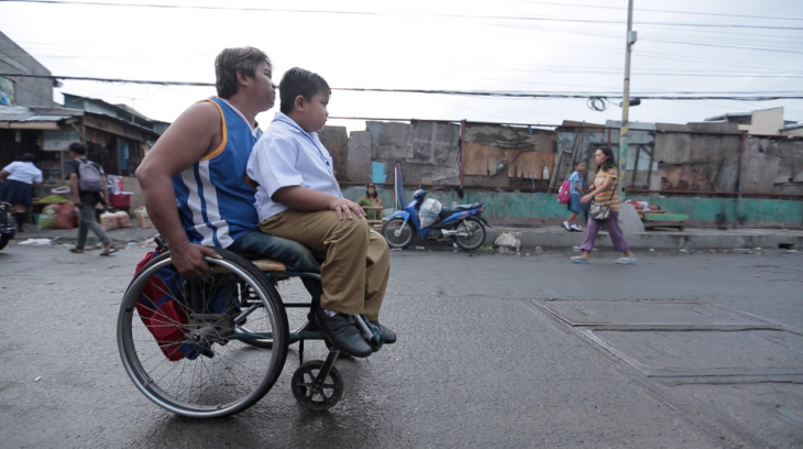 Niño rumbo a la escuela en silla de ruedas