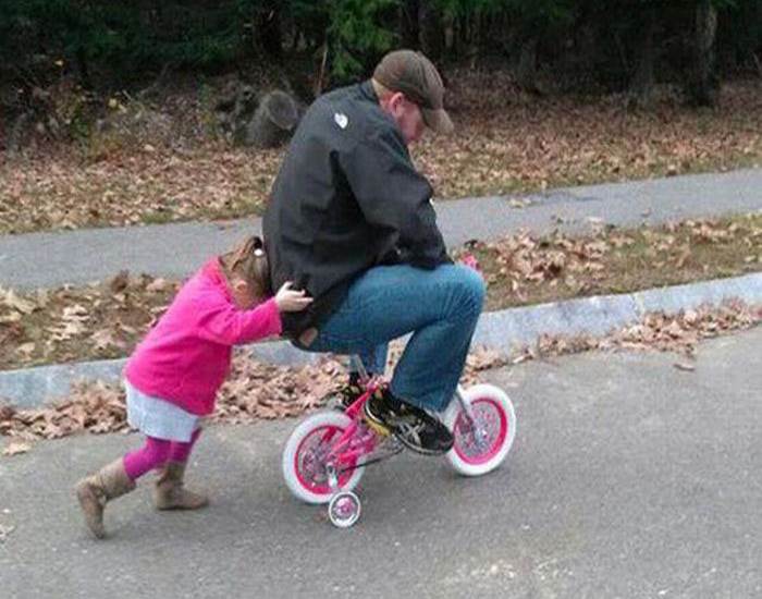 niña empujando a u hombre en bicicleta