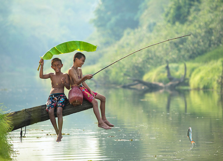 dos niños pescando en un rio