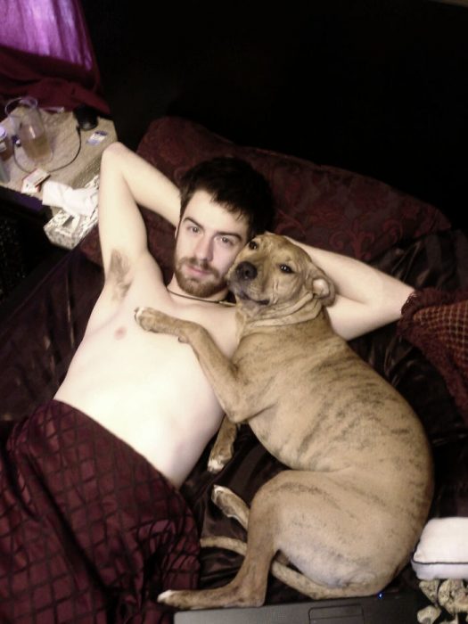 hombre sin camisa al lado de perro 