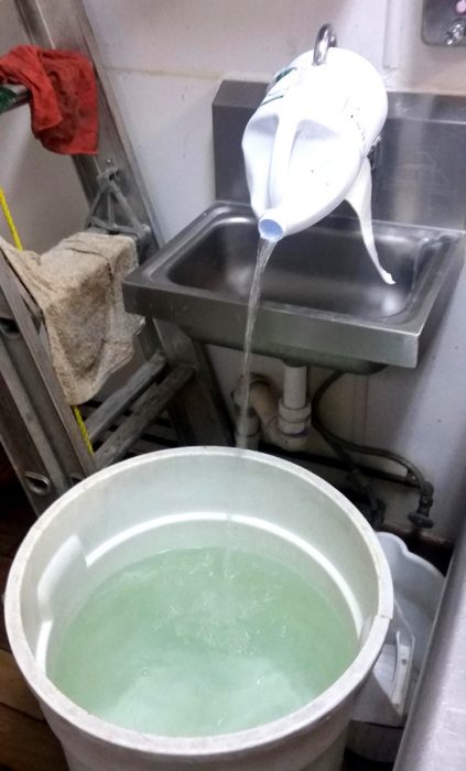 echar agua a una cubeta del lavabo con ayuda de una botella de plástico