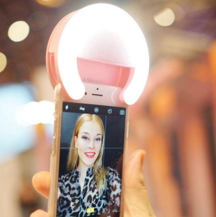 mano sostiene un celular con un anillo de luz para selfie