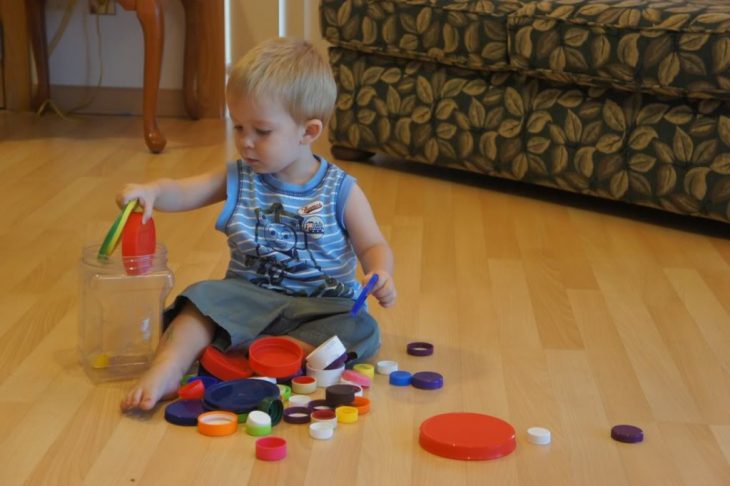 niño jugando con tapas de colores