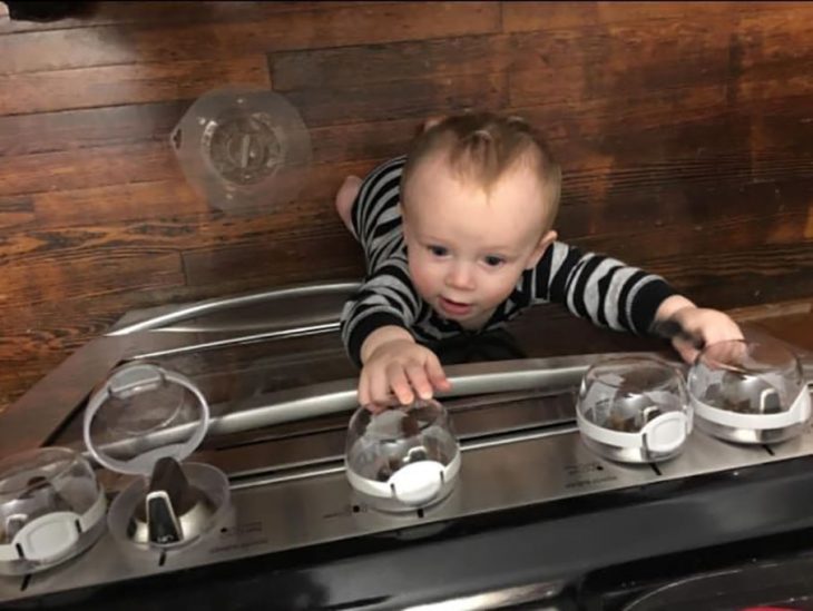 niño tratando de alcanzar cubiertas de manijas para estufa 