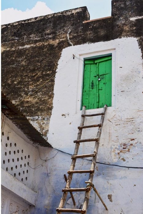 Puerta verde en el segundo piso con una escalera para subir a ella