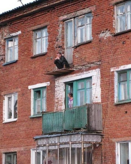 hombre en cuclillas en un balcón sin rejas 