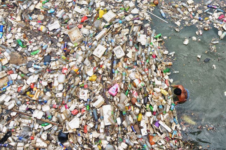 hombre en el océano con miles de botellas de plástico 