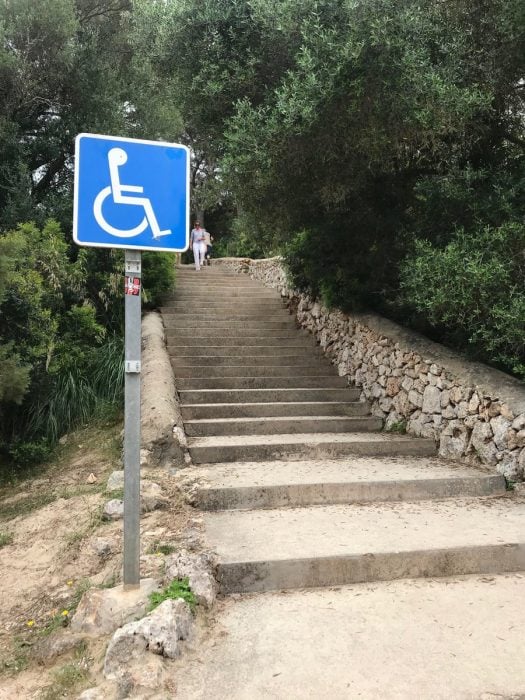 señal de discapacitados frente a unas escaleras 