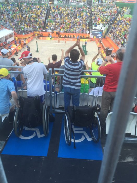 hombres de pie frente a sillas de ruedas en un partido deportivo