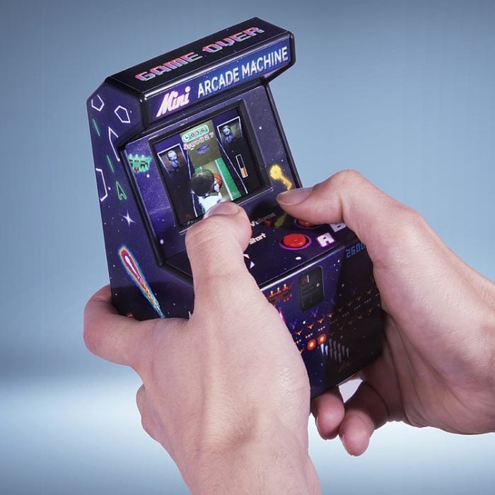 manos jugando con una mini consola arcade 