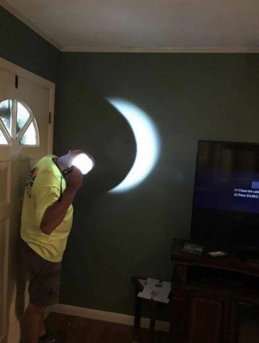 señor pryecta un eclipse en la pared con una linterna y su calva
